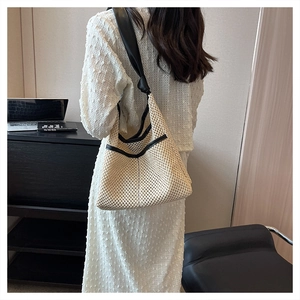 Detail of woven mesh tote bag with wide black leather straps for versatile use