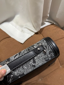 Close-up of black and white embroidery pattern with silver rivets on stylish handbag