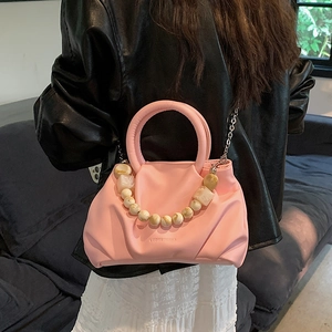 Rosa Wolken-Faltenhandtasche mit Perlenkette in Lifestyle-Szene dargestellt
