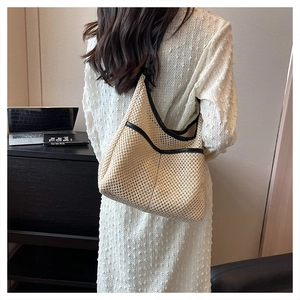 Detail shot of woven straw tote bag with black leather trim worn on the shoulder