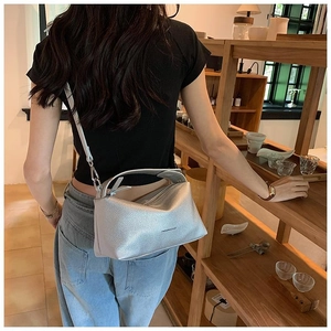 Détail latéral du sac polochon en cuir argenté à texture litchi avec marquage mode