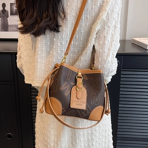 Sac seau vintage marron à monogramme avec bandoulière en cuir kaki porté par un mannequin