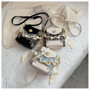 Detail of tweed crossbody bag featuring pearl flower buckle and silk scarf handle