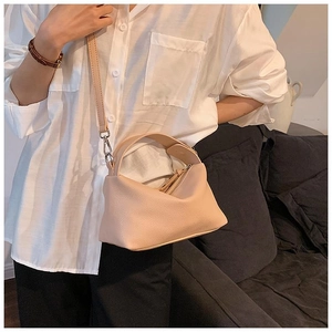 Détail de la texture cuir grainé souple du sac beige porté par un mannequin