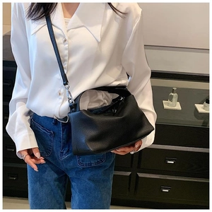 Détail de la texture cuir noir grainé sur le grand sac à main avec poignée et bandoulière