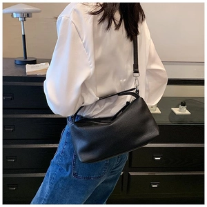 Gros plan du sac à bandoulière en cuir grainé noir porté par un mannequin pour le style