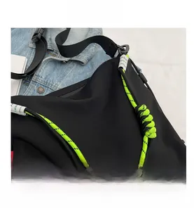 Detail of black nylon tote bag featuring fluorescent green rope handles and woven knots