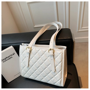 Detail of white quilted tote bag with gold ring hardware and elegant rhombic stitching