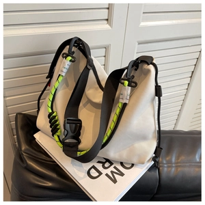 Detail of white nylon tote bag with black strap and neon green woven rope accents