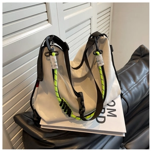 Detail of white nylon tote bag featuring adjustable black strap and neon green decor cord