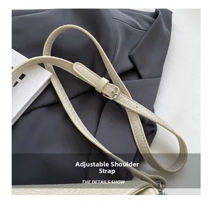 Detalle de la correa ajustable con hebilla plateada en bolso de hombro de piel granada