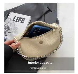 Vista de la capacidad interna del bolso de silla crema con móvil y cadena de plata
