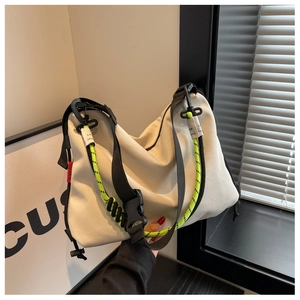Detail of off-white nylon tote bag with neon climbing rope and black shoulder strap