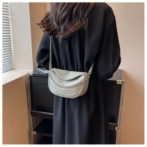 Bolso de silla beige con textura de lichi y cadena plateada usado por modelo