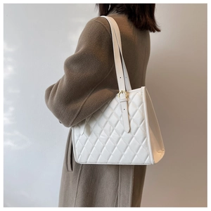 Detail view of a white quilted tote bag with adjustable strap and golden metal buckle