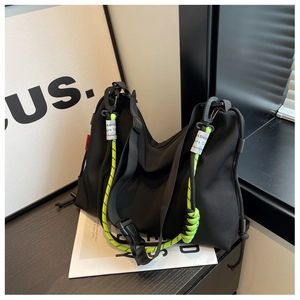 Detail of black nylon tote bag featuring neon green braided strap and adjustable buckles