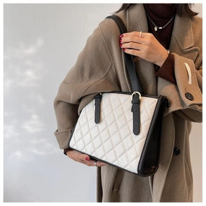 Quilted tote bag in black and white leather shown on model for a stylish casual look