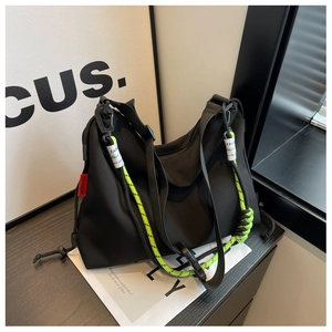 Close-up of black nylon crossbody bag with contrasting neon green braided rope detail
