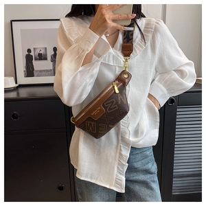 Detail van bruine crossbodytas met letterpatronen en een brede verstelbare schouderriem