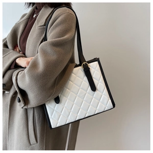 Detail of a large quilted tote bag in black and white leather with gold-tone hardware