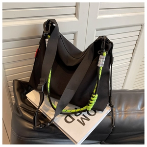 Close-up of black nylon tote bag with neon green woven rope and fashion label detail