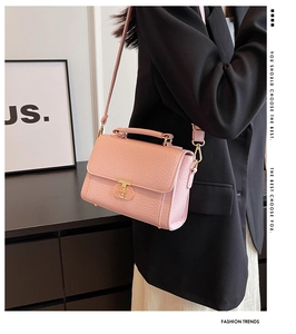 Détail d'un sac bandoulière rose en similicuir à motif crocodile avec fermoir doré sur mannequin