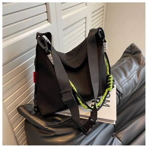 Detail of black nylon hobo bag with contrast neon green braided rope and wide shoulder strap