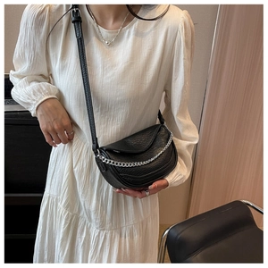 Detalle de bolso silla de montar negro con textura granulada y cadena plateada en modelo