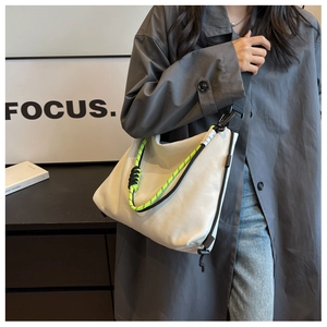 Detail of nylon tote bag featuring neon green rope accent and adjustable black strap