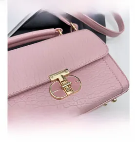 Gros plan d'un sac à main rose en cuir grainé avec fermoir rotatif en métal doré en T