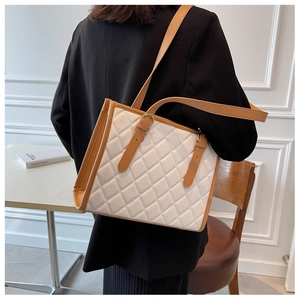 Detail of a large white quilted tote bag with brown straps for stylish daily commuting