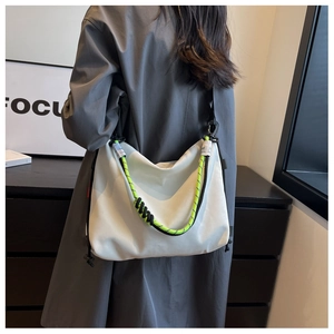 Close-up of light gray nylon tote with vibrant neon green braided rope strap detail