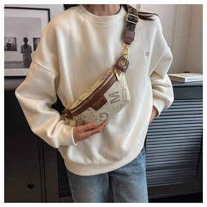 Detailopname van een stijlvolle beige borsttas met bruin leer en bedrukte schouderriem