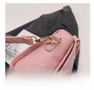 Détail du sac en cuir rose façon croco montrant les crochets dorés et les fines coutures