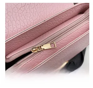 Gros plan du sac à main en cuir rose avec fermeture éclair dorée et texture gaufrée
