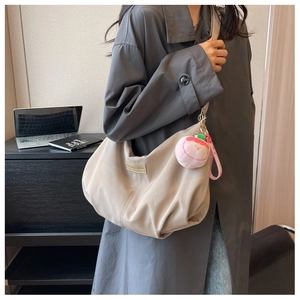 Beige nylon crescent bag on model showing premium matte texture and peach charm