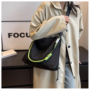Detail of black nylon crossbody bag with neon yellow rope straps and fashion tag