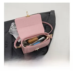 Détail du sac bandoulière en cuir rose montrant l'espace intérieur avec téléphone et portefeuille