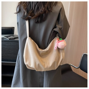 Detail view of large beige nylon dumpling bag with peach plush charm and fashion logo
