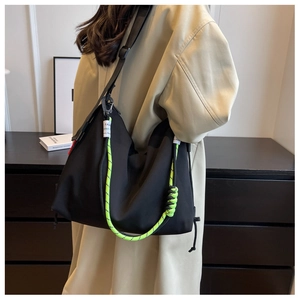 Detail of black nylon tote bag with high-visibility neon green drawstring and wide strap