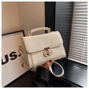 Détail du sac à bandoulière crème avec texture plissée et fermoir en T doré élégant