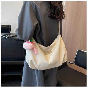 Nylon dumpling crossbody bag with peach plush charm and decorative logo detail