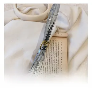 Detail of silver croc-embossed shoulder strap with golden metal buckle and adjustment holes