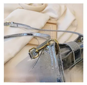 Detail of gold metal hook and silver crocodile embossed leather on shoulder bag