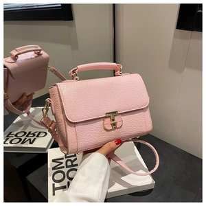 Détail d'un sac à main rose gaufré crocodile avec fermoir en T doré et poignée chic