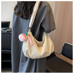 Detail of beige nylon crescent bag with adjustable wide strap and sweet plush charm