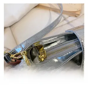 Detailed close-up of golden zipper hardware on silver faux crocodile leather shoulder bag