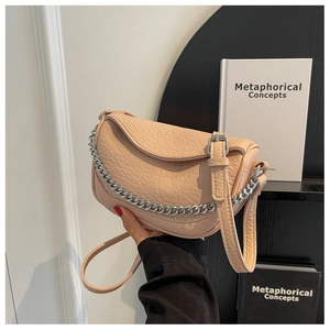 Detalle del bolso de silla en cuero granulado beige con cadena plateada y correa ajustable