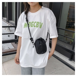 Outdoor shot of a black nylon mini crossbody bag with a sporty woven adjustable strap