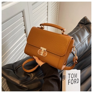Détail du sac à main en cuir grainé caramel avec fermoir rotatif et poignée haute